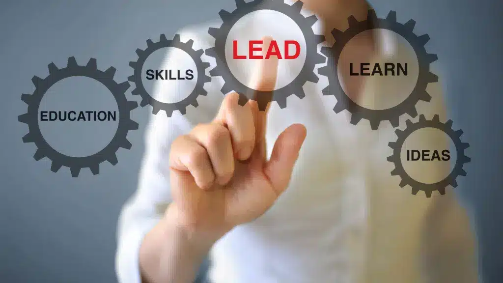 Person pointing at the word 'LEAD' in the center of hexagons labeled with words like 'Ideas,' 'Skills,' 'Learn,' 'Education,' symbolizing interconnected leadership skills.